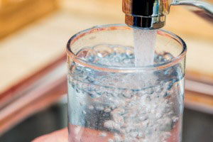 water coming out of faucet filling glass